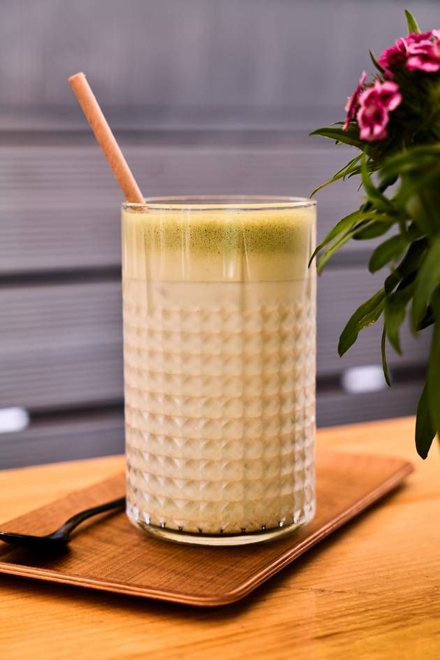 A refreshing glass of iced matcha latte with a straw, elegantly positioned on a table, inviting a cool sip.