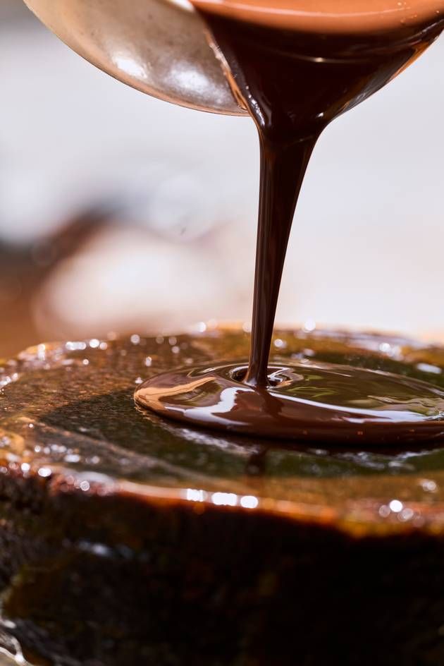 Rich chocolate sauce cascades over a Sacher Cake, creating a decadent final layer of indulgence.