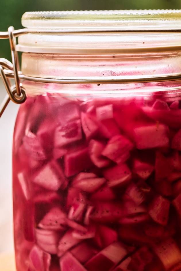 A jar of pickled onions displayed on a table, emphasizing the rich color and texture of the preserved vegetables inside.