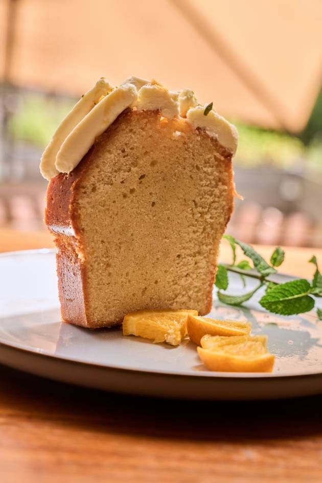 A tempting slice of lemon cake with white chocolate ganache on a plate, garnished with a slice of lemon.