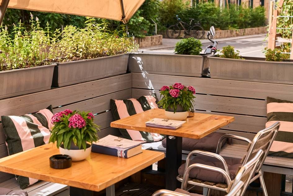 A cozy café terrace featuring a table with chairs adorned with a vibrant bouquet of flowers.