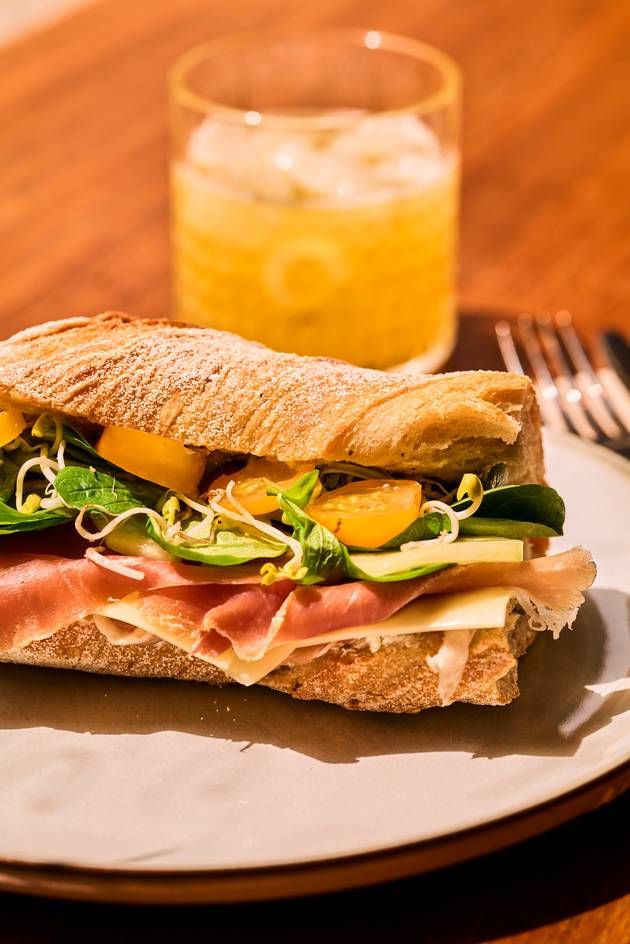 A glass of refreshing drink alongside the San Daniel baguette with fresh  salad.