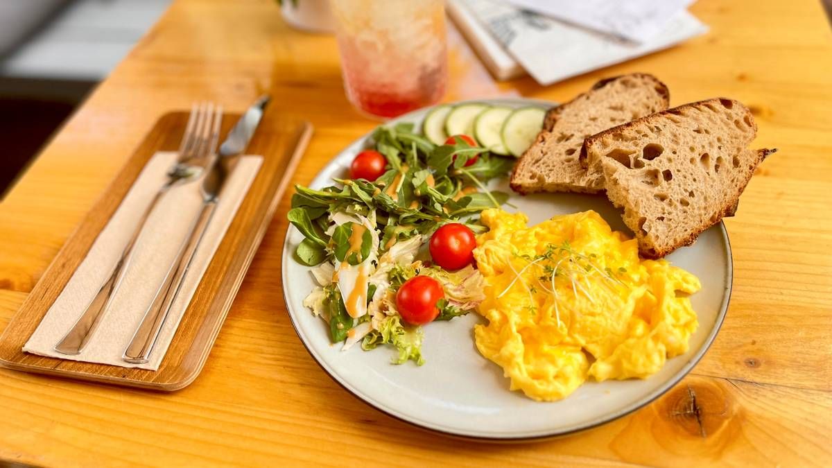 A well-presented plate with scrambled eggs, crispy bread, and a side of fresh salad, ideal for breakfast or brunch.