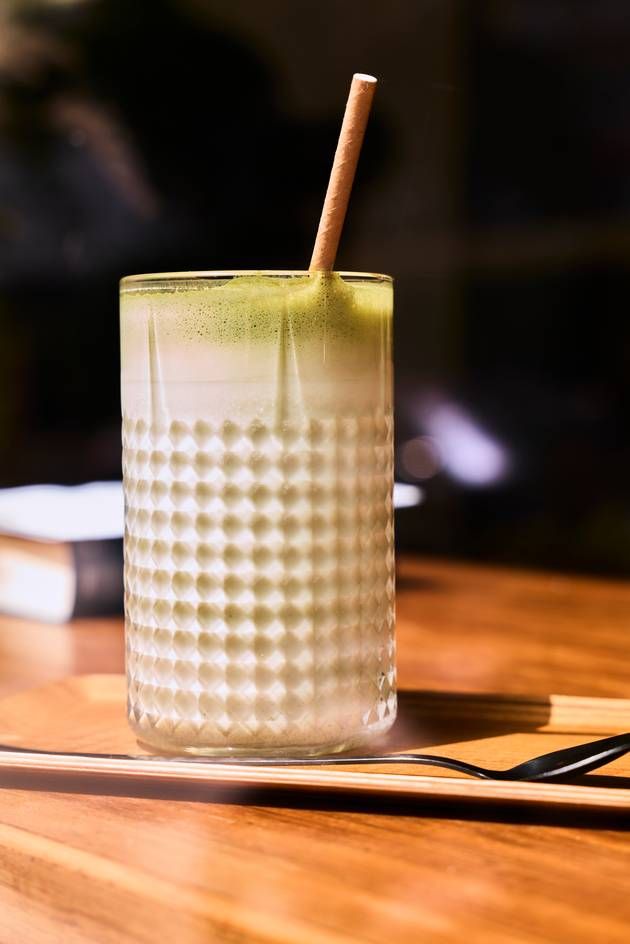 A glass of iced matcha latte with a straw, featuring a smooth, vibrant green drink perfect for a refreshing sip.