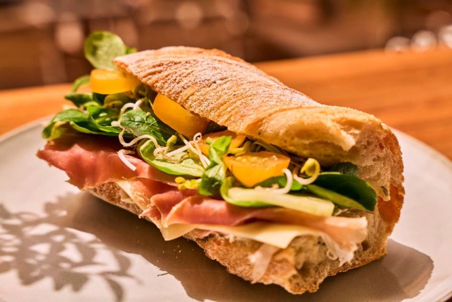 A landscape-oriented view of the San Daniel baguette with fresh salad on a plate.