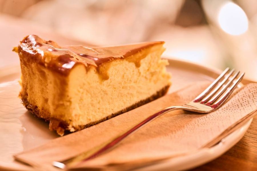 A slice of salted caramel cheesecake on a plate, captured from an angle.