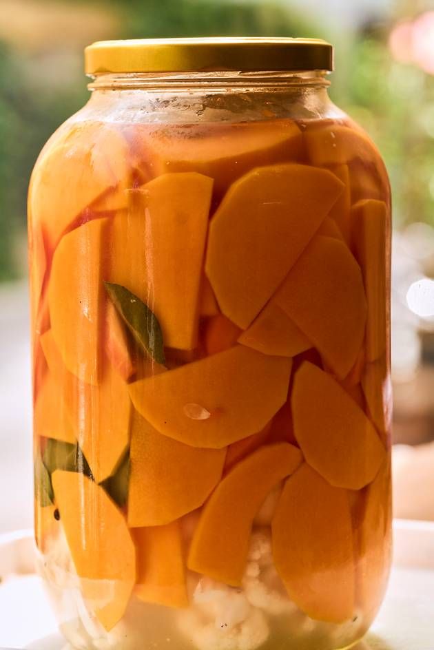 A table features a jar filled with an array of fermented vegetables, emphasizing the colorful and healthy contents within.